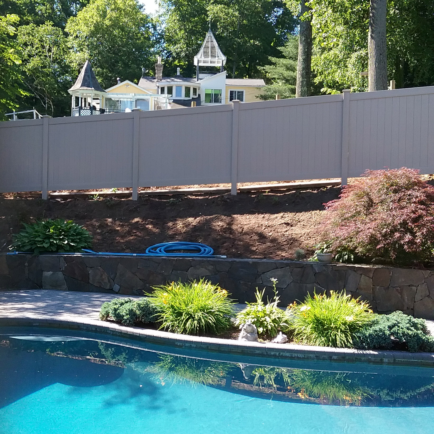 A pool with a reliable installation of a fence for enhanced safety, surrounded by trees.