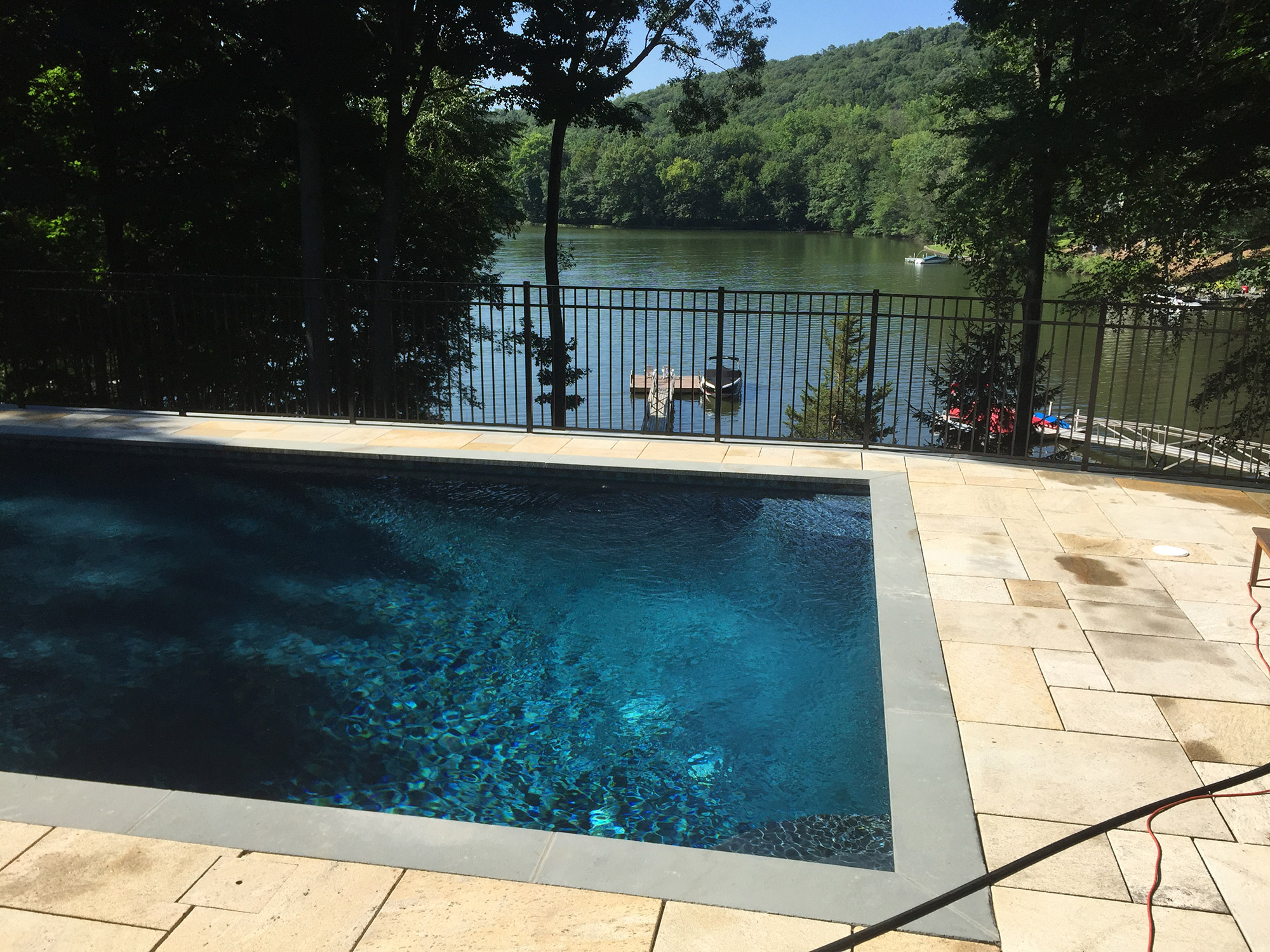 A pool with a railing overlooking a lake, enhancing safety.