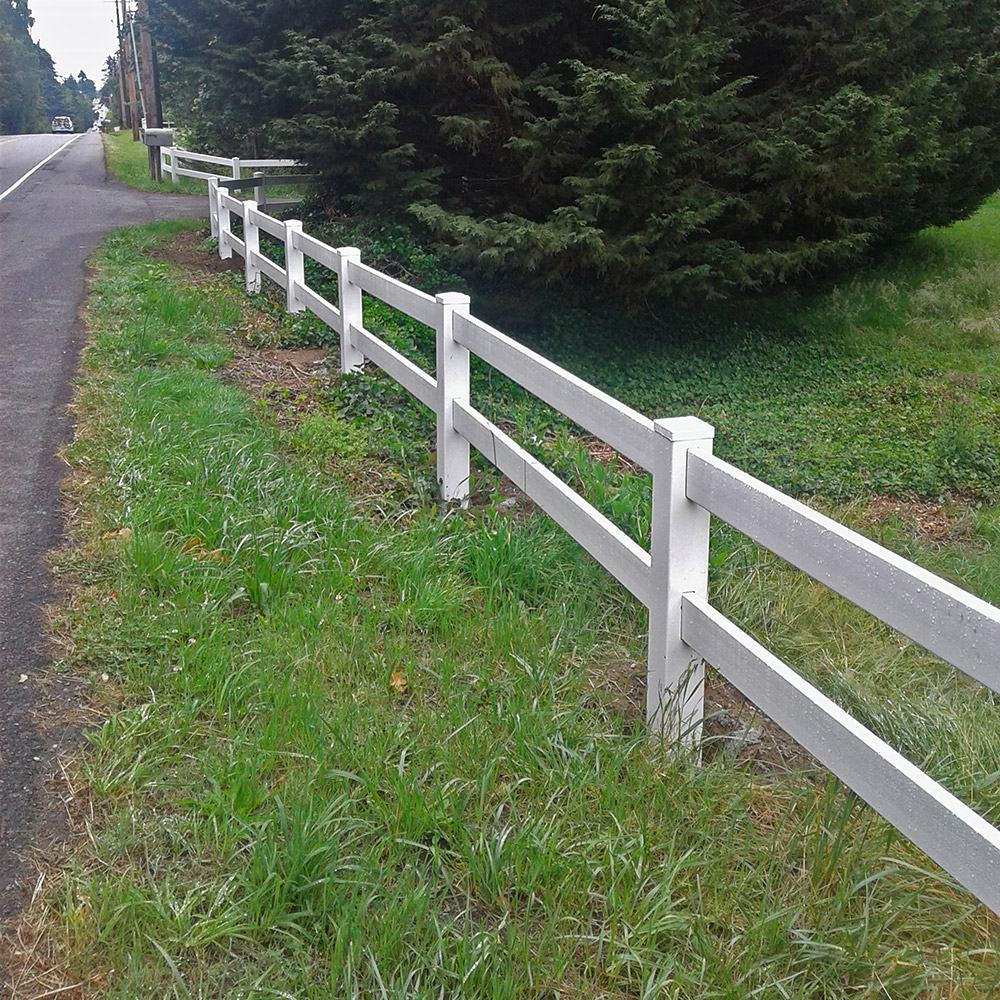 An affordable white fence along a road, perfect for split rail fencing.