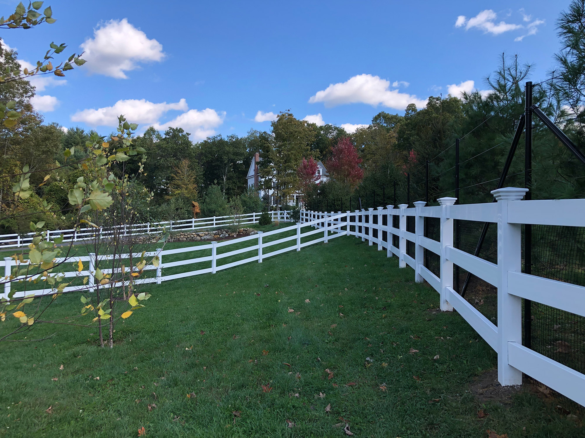 A white fence in a grassy field, perfect for split rail fencing.