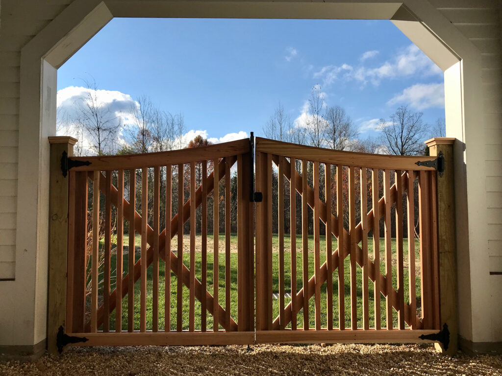 A gate with a wooden fence and grass in the background.