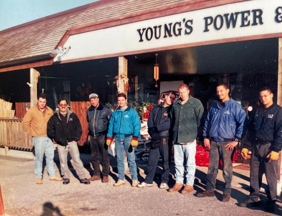 A group of men gather outside of a young's power and equipment store.
