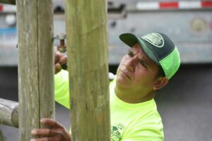 A man in a green shirt is working on a wooden fence.