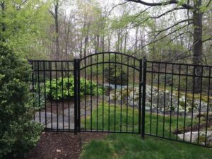 photo of a black colored aluminum fence in a garden.