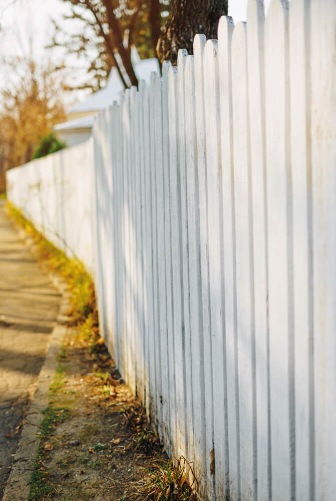Photo of a white fence along a road.